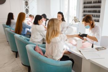 Group of girlfriends relax on manicure procedure in beauty salon. Professional beautician and female customers, nail care in spa, fingernail treatment