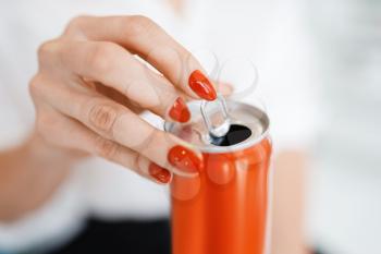 Woman opens a soda can after manicure in beauty salon. There is a danger of breaking nail. Female customer with red nails holds beverage in spa studio, fingernail care