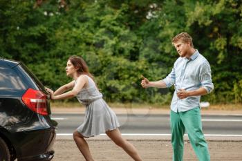 Young couple pushing broken car on road, breakdown. Crashed automobile or emergency accident with vehicle, trouble with engine on highway