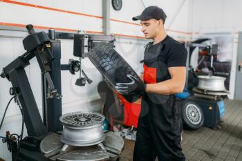 Mechanic change tire, repairing service. Man repairs car tyre in garage, professional automobile inspection in workshop