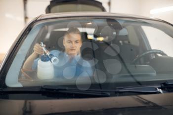 Female washer cleans automobile interior, view through the windshield, car wash. Woman washes vehicle, carwash station, car-wash business