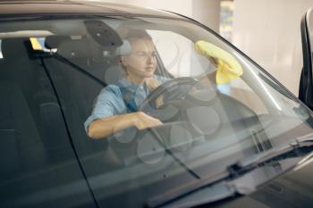 Female washer with polish spray cleans automobile interior, car wash service. Woman washes vehicle, carwash station, car-wash business
