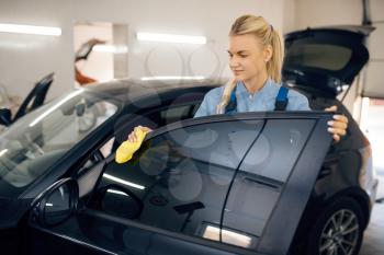 Female washer with sponge cleans automobile interior, car wash service. Woman washes vehicle, carwash station, car wash business