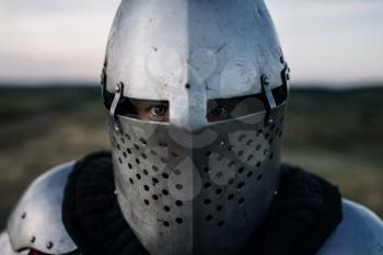 Medieval knight in armor and helmet closeup view, great battle. Armored ancient warrior in armour posing in the field