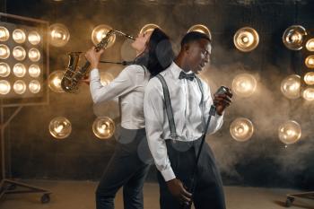 Male jazz performer and female saxophonist with saxophone, performing on the stage with spotlights. Jazz players playing on the scene