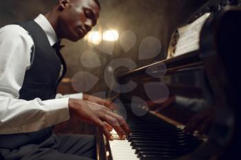 Black grand piano player, jazz performance in club. Negro performer playing musical instrument