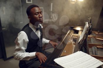 Ebony grand piano player performing classical music. Negro performer poses at musical instrument, jazz musician