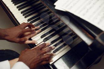 Ebony grand piano player hands on the keys, classical music. Negro performer poses at musical instrument