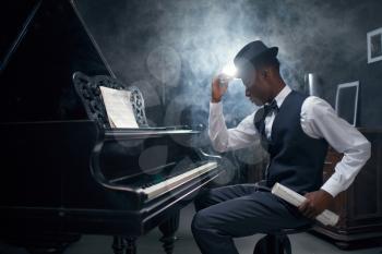 Ebony grand piano player, jazz musician. Negro performer poses at musical instrument before playing