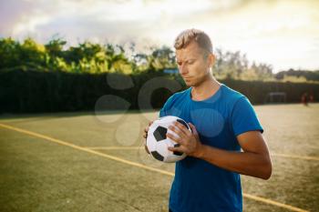 Male soccer player with ball in hands on the field. Footballer on outdoor stadium, workout before game, football training