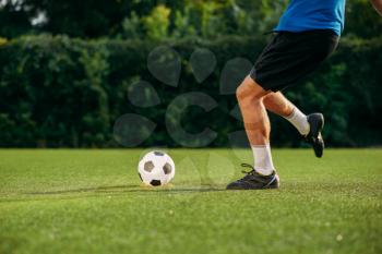 Male soccer player hits the ball on the field. Footballer on outdoor stadium, workout before game, football training