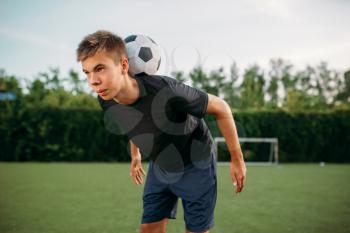 Male soccer player keeps balance with the ball on his neck on the field. Footballers on outdoor stadium, team workout before game