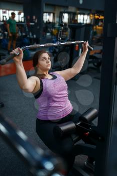 Overweight woman doing exercise in sport club, active training. Female person struggles with excess weight, aerobic workout against obesity, gym