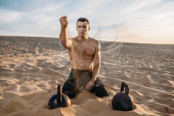 Sportsman sitting on sand after workout in desert at sunny day. Strong motivation in sport, strength outdoor training