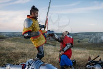 Old medieval knight in armor prepares to cut off head, great battle. Armored ancient warrior in armour posing in the field