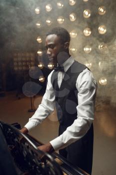 Black grand piano player playing on the stage with spotlights on background. Black performer poses at musical instrument before concert