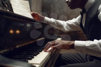 Black pianist, jazz performer on the stage with spotlights on background. Black musician poses at musical instrument before concert