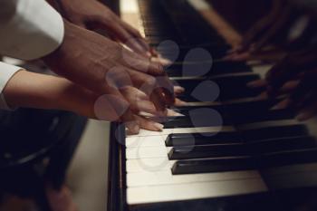 Black grand piano player hands on the keys, classical music. Black performer poses at musical instrument