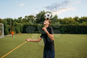 Male soccer player stuffs the ball with his head on the field. Footballers on outdoor stadium, team workout before game