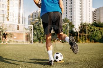 Male soccer player hits the ball on the field. Footballer on outdoor stadium, workout before game, football training