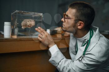 Male psychiatrist in lab coat holds container with the human brain, mental hospital. Doctor in clinic for the mentally ill