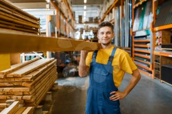 Male builder holds wooden boards in hardware store. Customer look at the goods in diy shop
