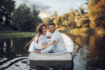 Happy love couple boating on lake at summer day. Romantic date, boat trip, man and woman walking along the river