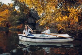 Love couple in boat on quiet lake at summer day, daydream, side view. Romantic date, boating trip, man and woman walking along the river