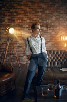 Elegance business woman in strict clothes poses in studio, retro fashion, gangster style, mafia. Vintage lady in office with brick walls
