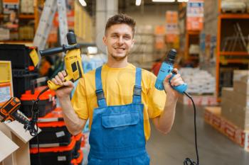 Male builder with power tools in hardware store. Constructor in uniform look at the goods in diy shop