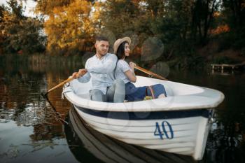 Love couple hugs in a boat on quiet lake at summer day. Romantic meeting, boating trip, man and woman walking along the river
