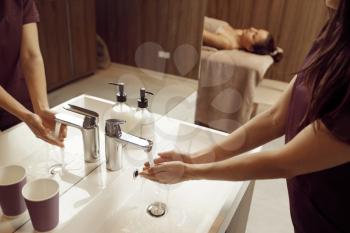 Female masseur washes her hands before massage procedure in spa salon. Massaging and relaxation, body and skin care