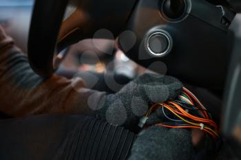 Professional car thief hacking ignition lock, criminal lifestyle. Hooded male robber breaks vehicle security system on parking. Auto robbery, automobile crime