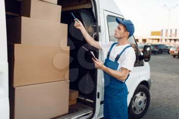 Deliveryman in uniform check boxes in the car, delivery service. Man standing at cardboard packages in vehicle, male deliver, courier or shipping job