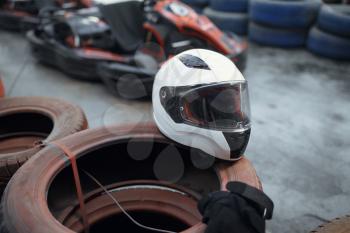 Helmet on tires, go kart car on background, karting auto sport indoor. Speed racing go-kart track. Fast vehicle competition, hot pursuit