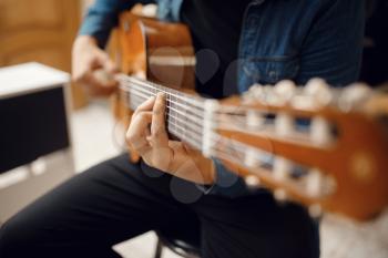 Male guitarist trying to play on acoustic guitar in music store. Assortment in musical instruments shop, musician buying equipment