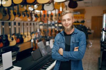 Young man poses at the showcase in music store. Assortment in musical instruments shop, musician buying equipment, music performer in market