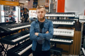 Bearded young man choosing synthesizer in music store. Assortment in musical instrument shop, male musician buying equipment