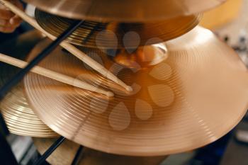 Copper drum cymbals and drumsticks on showcase in music store, closeup view, nobody. Assortment in musical instrument shop, professional equipment for musicians and performers