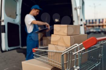 Parcel boxes and notebook in cargo cart, delivery service concept, delivering business, nobody. Cardboard packages, deliver, courier or shipping job