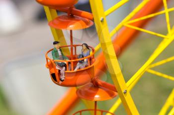 Love couple riding a ferris wheel, miniature scene outdoor, europe. Mini figures with high detaling of objects, realistically diorama, toy model