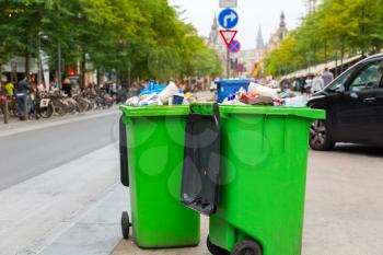 Green garbage can on sidewalk, european city. Full trash box on the street in Europe, nobody, trashcan, big plastic bin outdoor