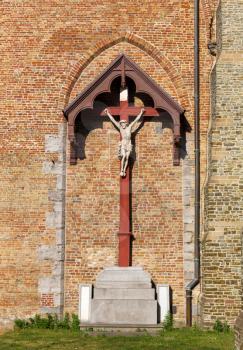 Crucifixion at brick wall, old provincial European town, bottom view. Summer tourism and travels, famous europe landmark, popular places for vacation tour or holidays