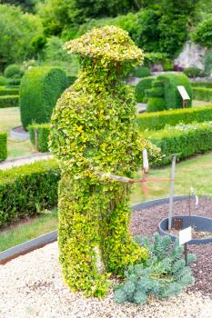 Figure in shape of lawn mower from the bushes, summer park in Europe. Professional gardening, european green landscape, garden plants decoration