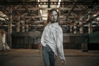 Female zombie walking in abandoned factory, scary place. Horror in city, creepy crawlies attack, doomsday apocalypse, bloody evil monsters