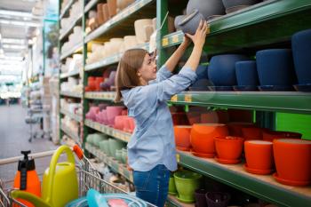 Female customer at the shelf with pots, shop for gardening. Woman buying equipment in store for floriculture, florist instrument purchasing