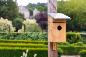 Wooden birdhouse in green park at summer day, Europe. Nesting box for birds, nest house closeup