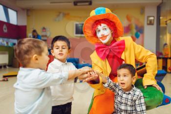 Funny clown and little boys play counting game together. Birthday party celebrating in playroom, baby holiday in playground. Childhood happiness, childish leisure