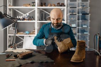 Shoemaker fix the shoe, footwear repair. Craftsman skill, shoemaking workshop, master works with boots, cobbler job