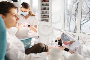 Two women on pedicure procedure in beauty salon. Professional beauticians and female customers